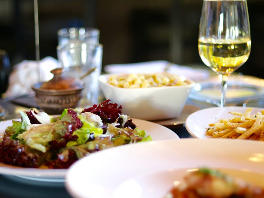 A beautiful, fresh salad sits alongside a glass of white wine at fig cafe & winebar, Glen Ellen