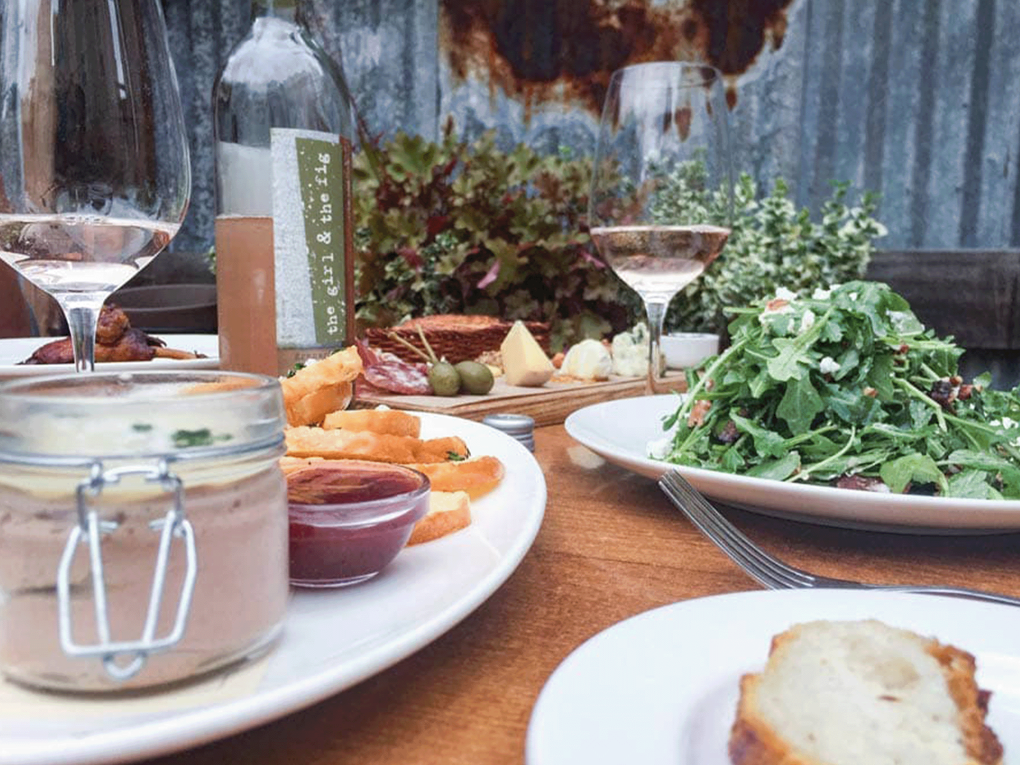 A table set outside with appetizers, salad, and wine