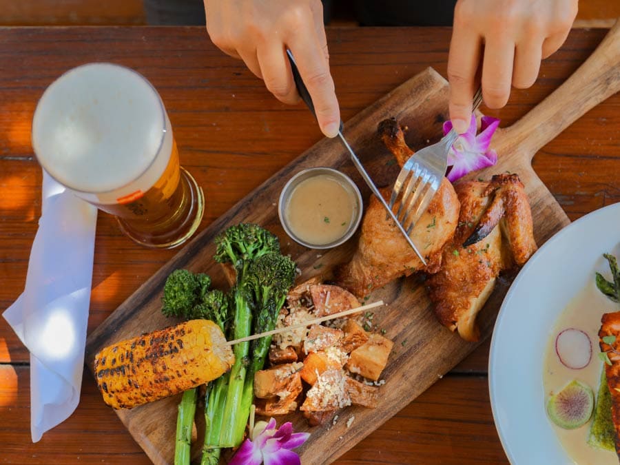 A person slices chicken served on a board