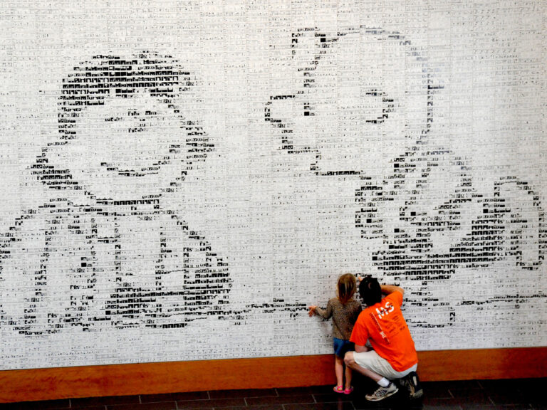 people looking through the iconic images of the peanuts comics at the museum
