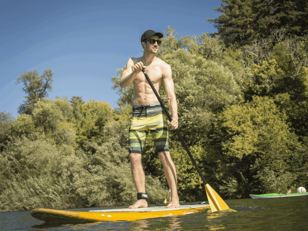 person using a stand up paddle board down the russian river in sonoma county