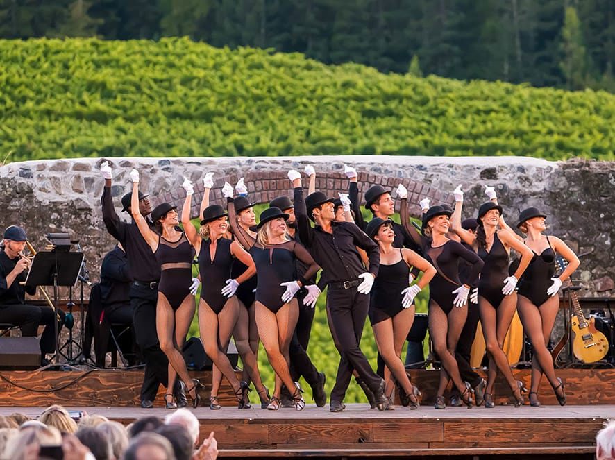 People sing and dance on stage in the winery ruins