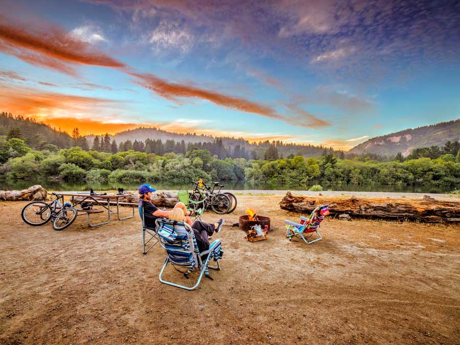 People sit around a fire pit as the sun sets