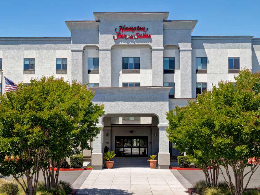 The exterior of the front of the hotel has palm trees on each side