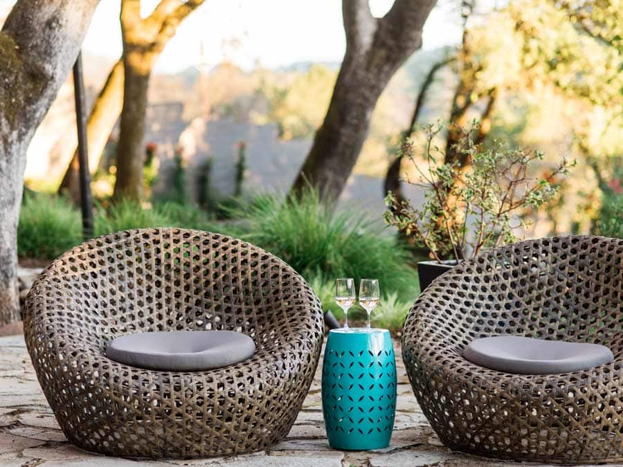 Two stylish chairs with a table with two glasses of rose on it underneath oak trees in Sonoma County