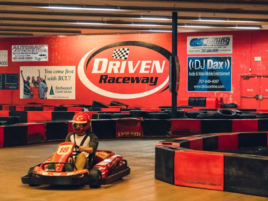 A young person zooms around the go cart track with a helmet on in Sonoma County