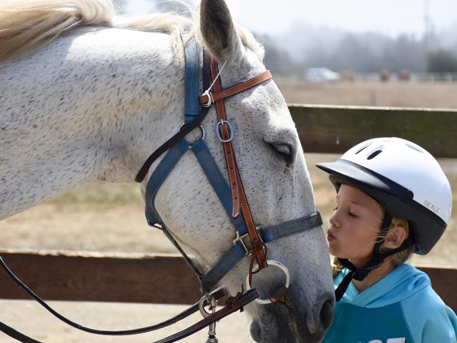 A young girl kisses her horse at Chanslor Stables, Bodega Bay