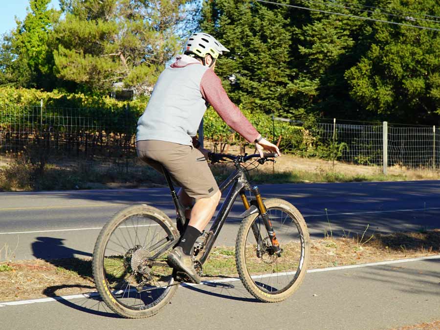 A person wears a helmet and rides along a paved trail