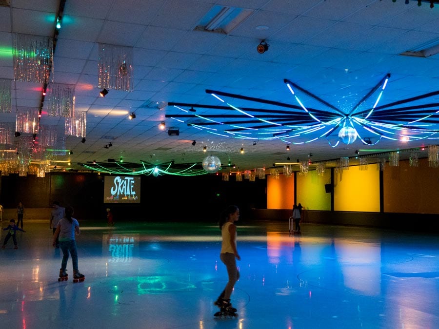 Two girls roller skate under neon lights at Cal Skate, Rohnert Park