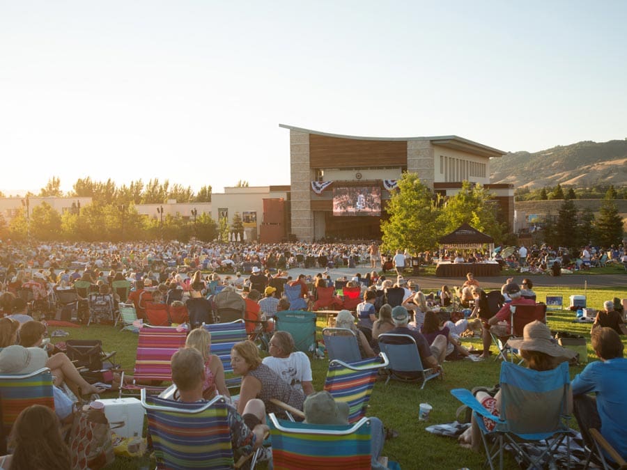 People sit in low-backed chairs on the lawn at sunset