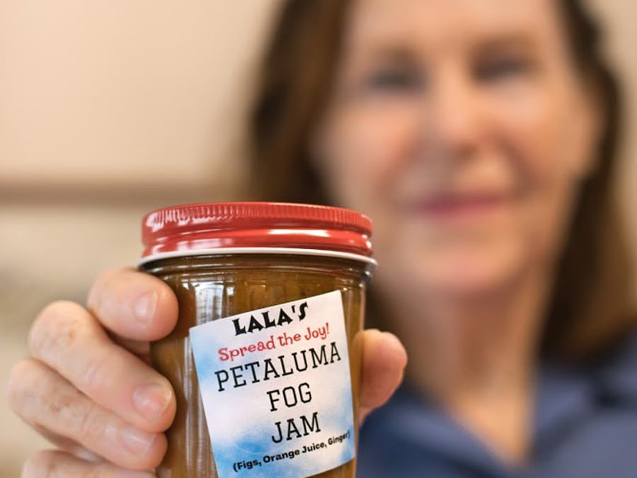 A woman holds a jar of jam that she made