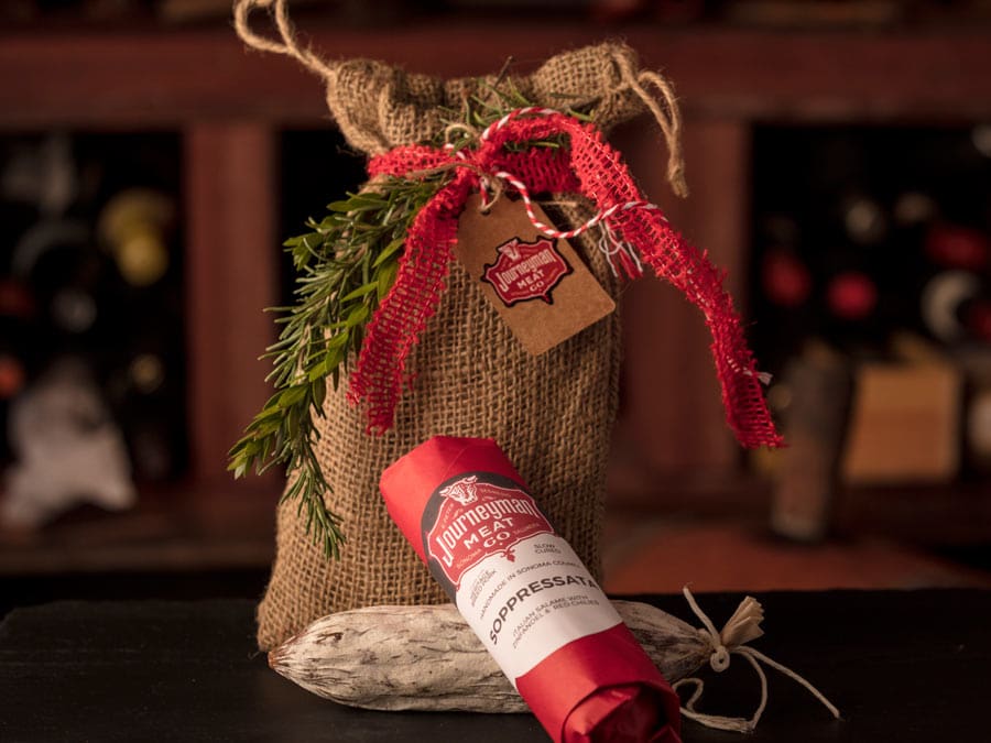 A burlap sack and salami decorated in red ribbon