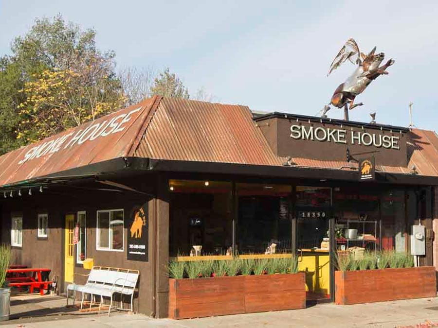 The outside of the restaurant has a sculpture of a flying pig on the roof