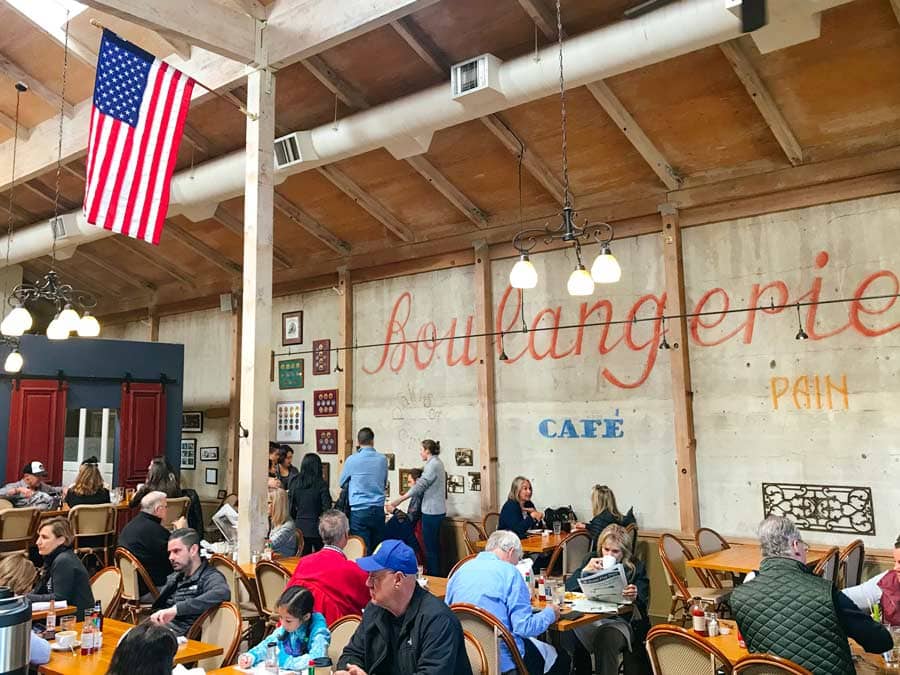 People sip coffee inside the bakery where Boulangerie is painted along the wall