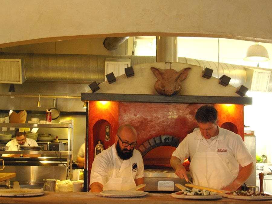 Chefs prepare pizza in front of a wood burning oven at Diavola Pizzeria & Salumeria, Geyserville