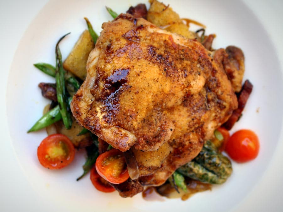 Roasted chicken on top pf a bed of green beans and tomatoes in Sonoma County