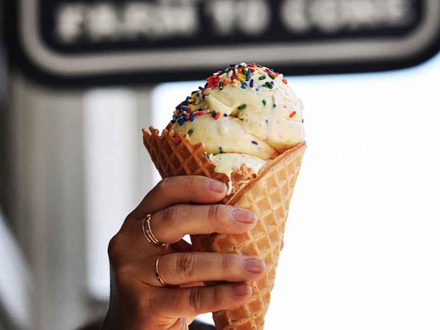 Vanilla ice cream with rainbow sprinkles on top in a waffle cone