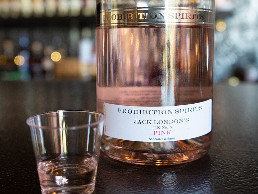 a bottle of light pink gin sits on a dark counter