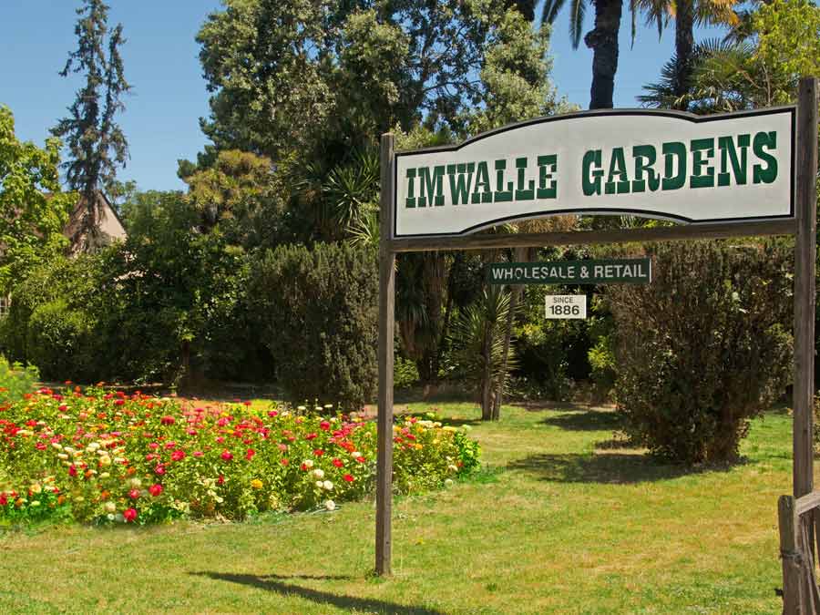 The sign for Imwalle Gardens next to flowers blooming in Sonoma County