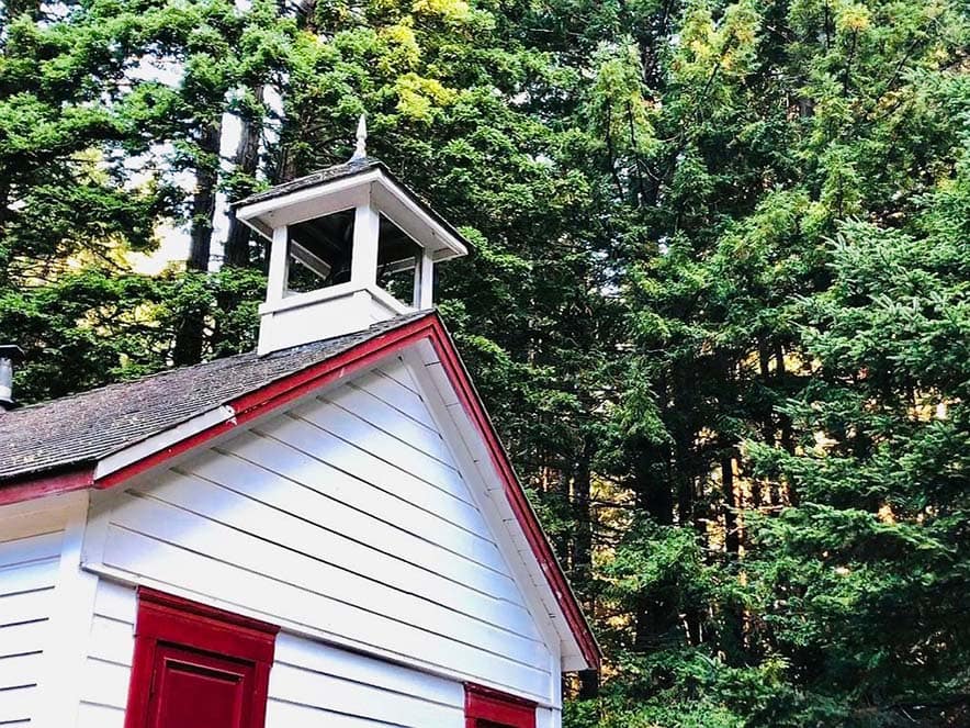 red and white schoolhouse among trees