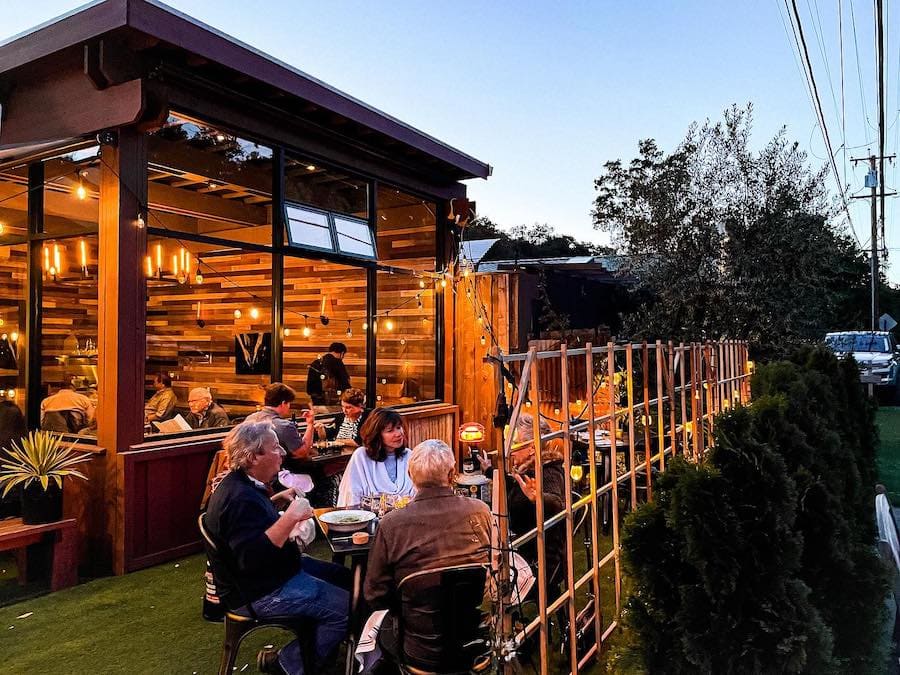 Diners enjoying dinner at dusk both inside and outside the rustic-chic restaurant Glen Ellen Star 