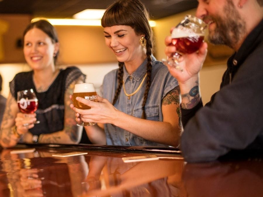 A woman with braids holds a glass of beer