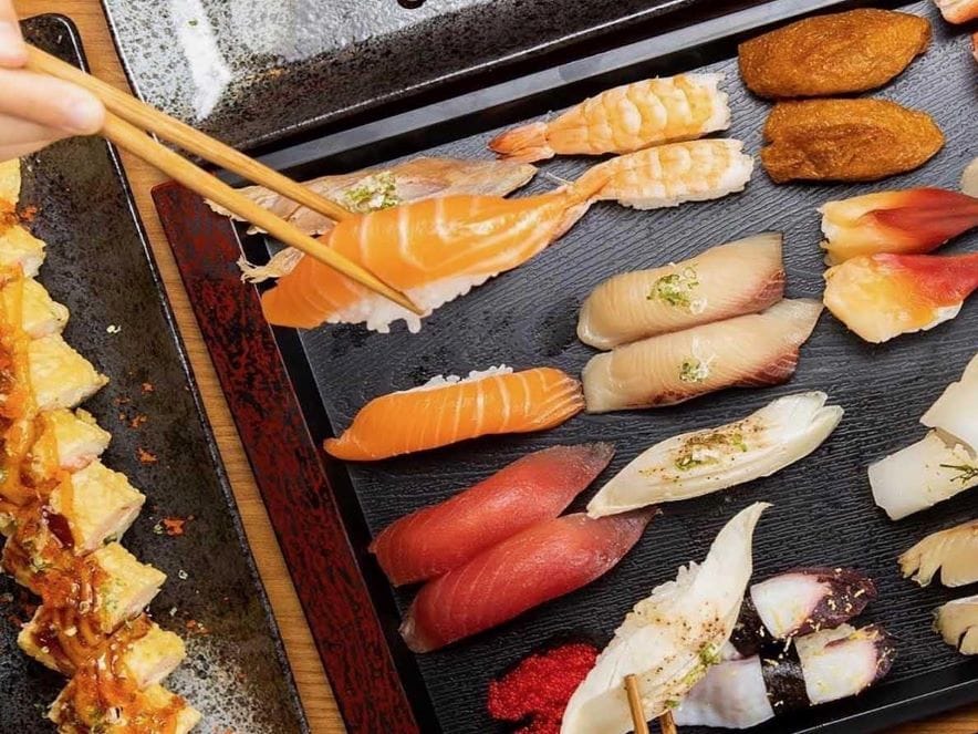 Picture of person reaching for sushi with chopsticks