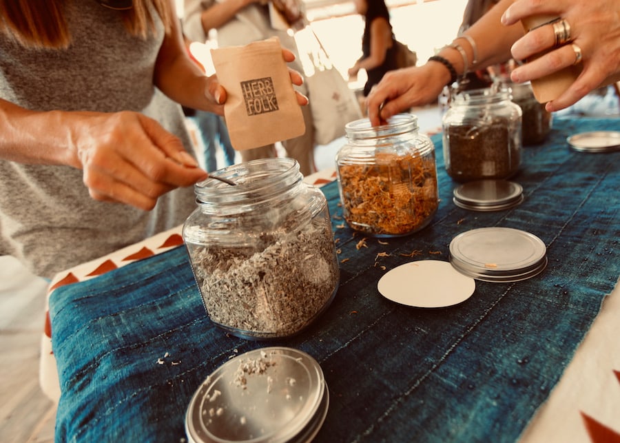 Colorful herbs in glass jars on an outdoor table, at a farm event put on by Herb Folk in Petaluma 