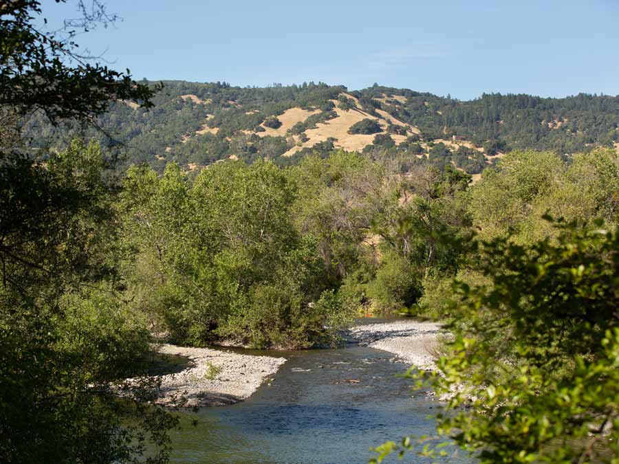 The river flows through a tree lined valley