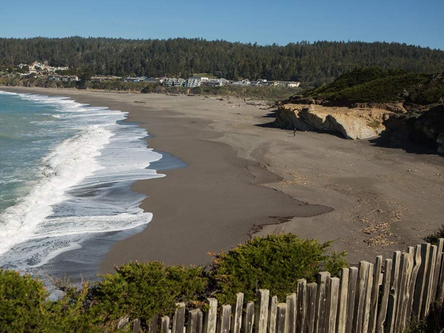 A sandy beach is surrounded by jagged cliffs in Sonoma County