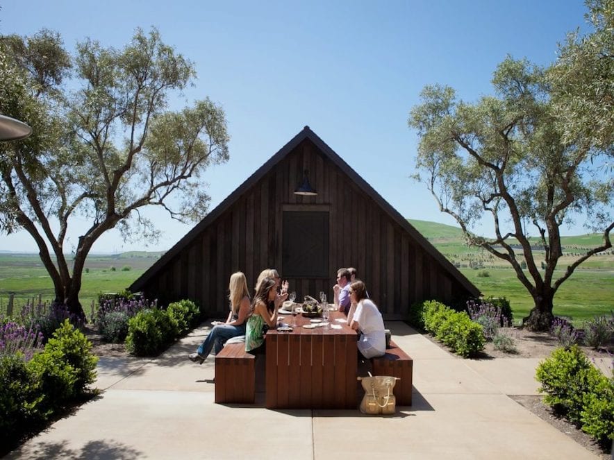 Outdoor food and wine pairing at a picnic table beside a barn at Rams Gate Winery