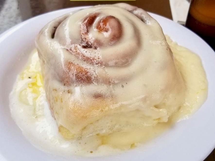 close up of cinnamon roll with melting frosting