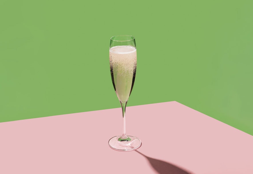 Flute of sparkling wine on a pink and chartreuse background 