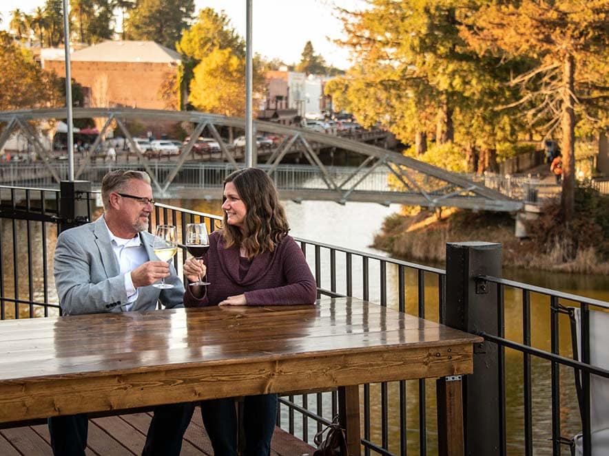 two people sitting on patio along river