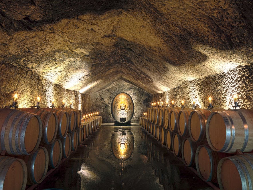 Casks and barrels age the wine in a dimly-lit cave in Sonoma County