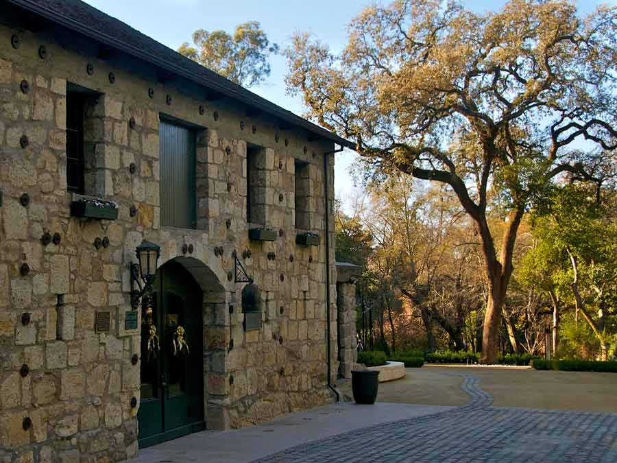 The outside of the historic stone winery has an oak tree growing nearby