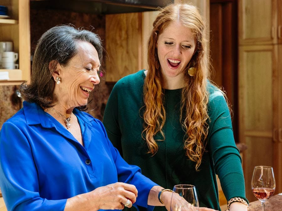 Two women smile while cooking