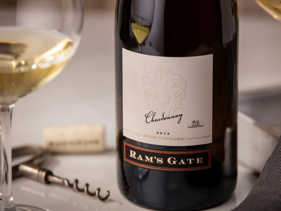 A close up photo of a bottle of wine and a freshly poured glass sit next to a corkscrew