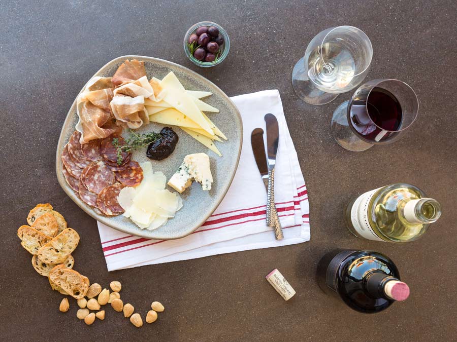 Bottles of wine, cheese, nuts, crackers, and salami from above
