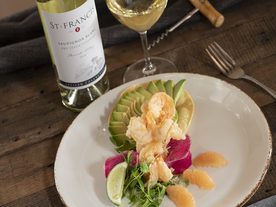 Fried shrimp, avocado, and citrus fanned on a white plate, served with St. Francis Winery sauvignon blanc