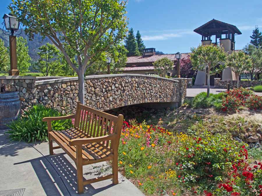 A stone bridge leads the way into the winery surrouded by blooming flowers