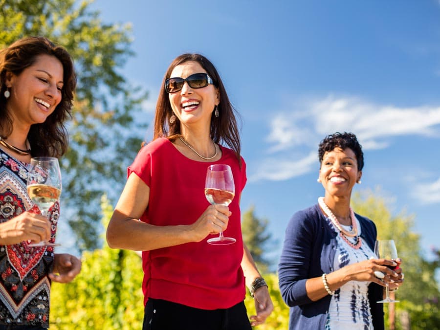 Three women smiling holding glasses of wine