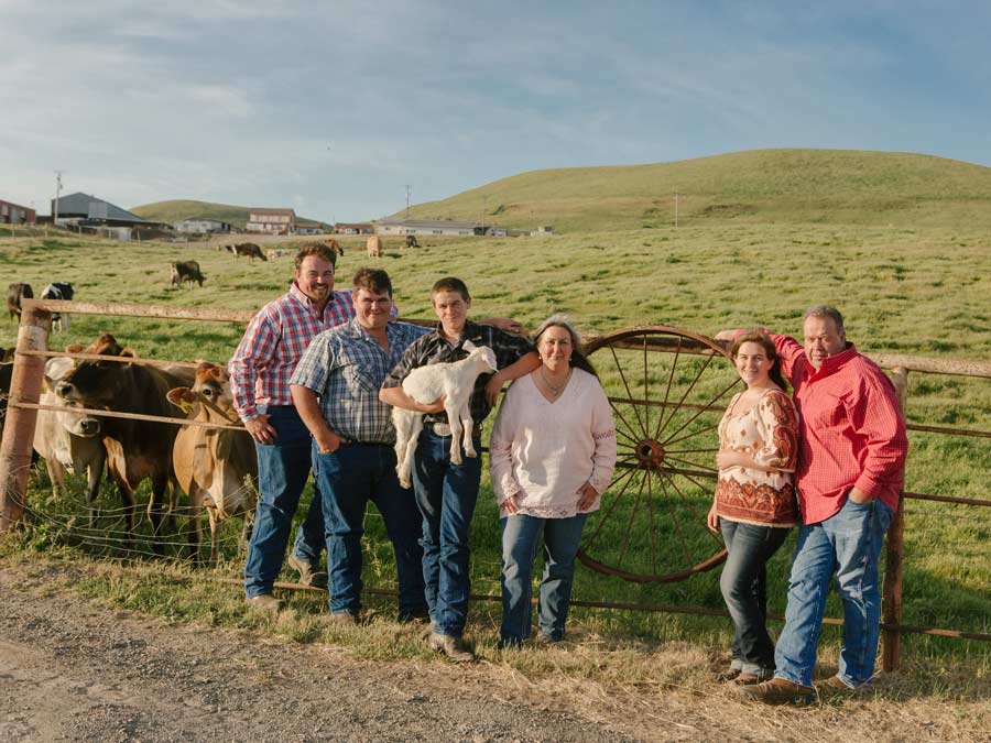 The farming family stands next to a fence