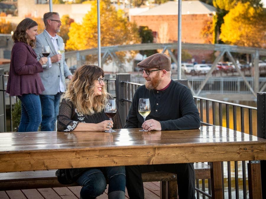 People sip on wine at a table along the river