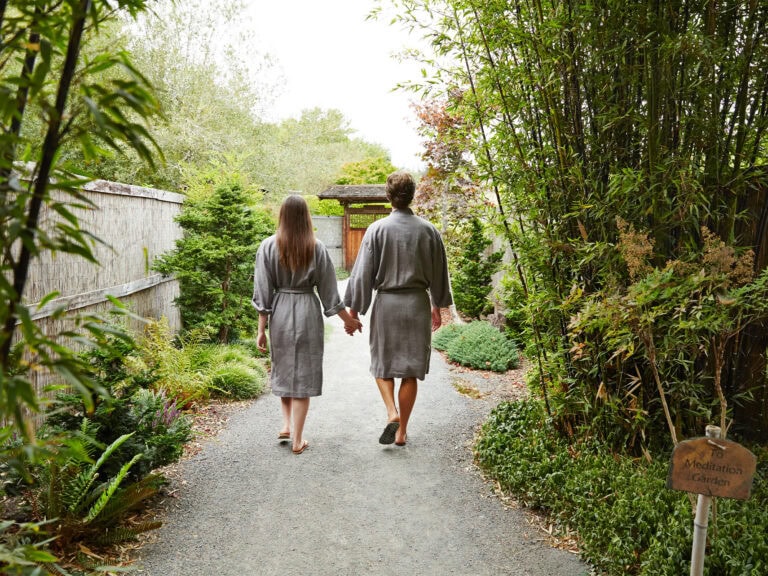 couple holding hands walking into osmosis meditation garden in sonoma county