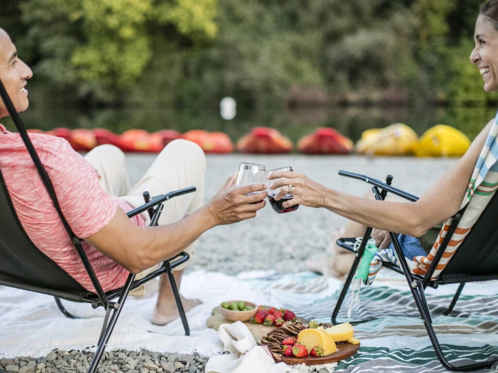 couple having a wine and food picnic at johnson beach at the russian river in sonoma county