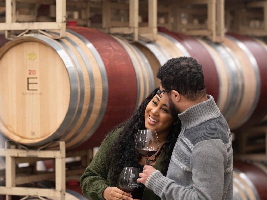 couple enjoying a glass of wine in the barrel room at emeritus vineyards in sonoma county