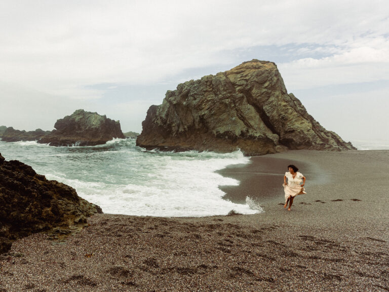 woman skipping along the sonoma county coast line at wrights beach in bodega bay