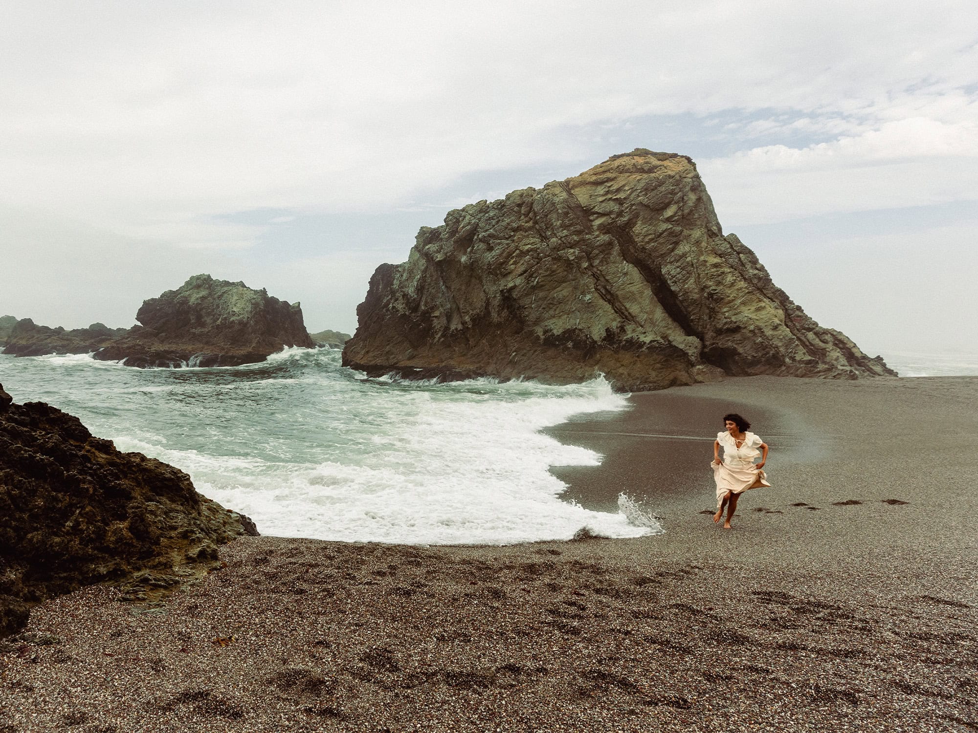 woman skipping along the sonoma county coast line at wrights beach in bodega bay