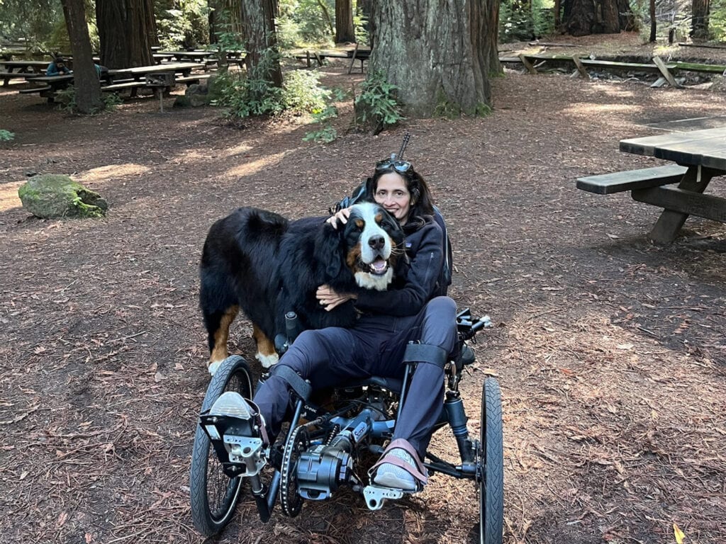 visitor in a wheelchair with their service dog enjoying the armstrong redwoods state park in guerneville